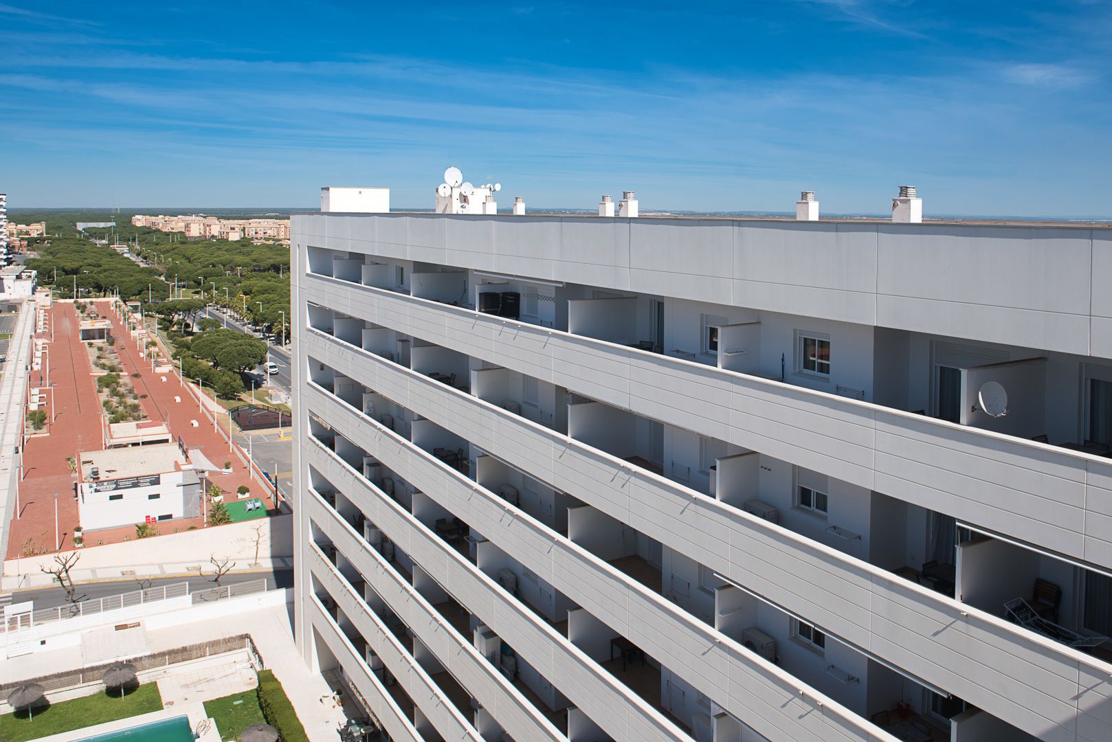 A multi-story building with a flat roof, multiple balconies, and a clear view of the surrounding area.