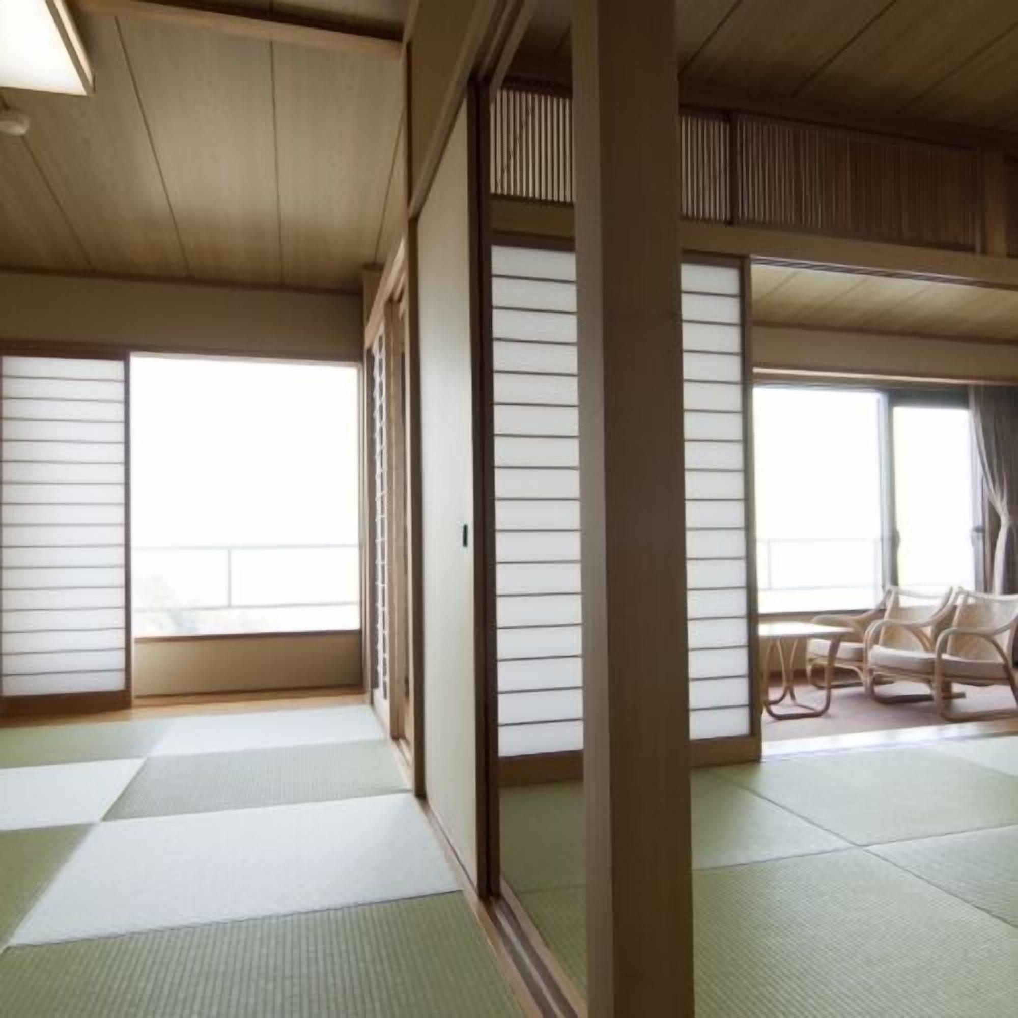 Una habitación japonesa tradicional con suelo de tatami, puertas correderas y vistas al exterior.