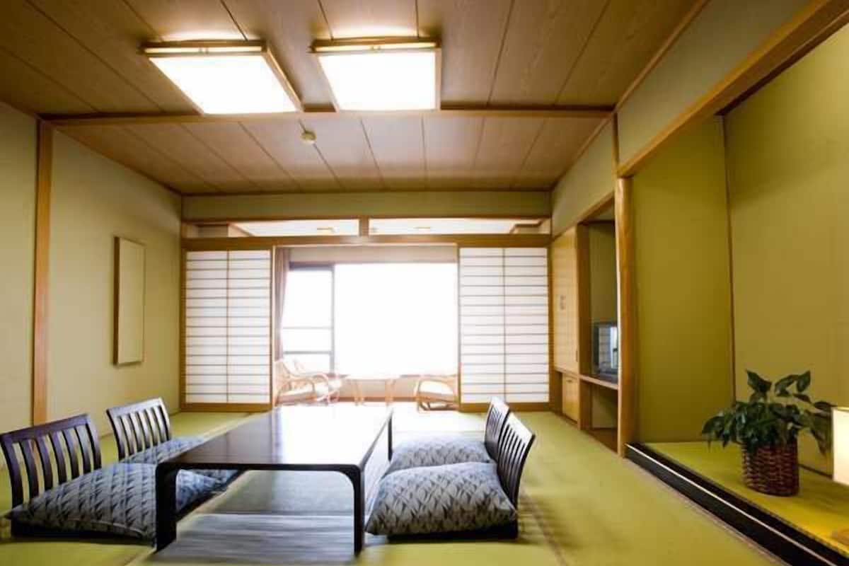 A traditional Japanese-style room with tatami flooring, a low table, and a sofa.