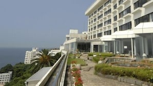 A modern hotel with a rooftop terrace, a pool, and a view of the sea. - Nishiura Onsen Hotel Tokaien (Gamagori)