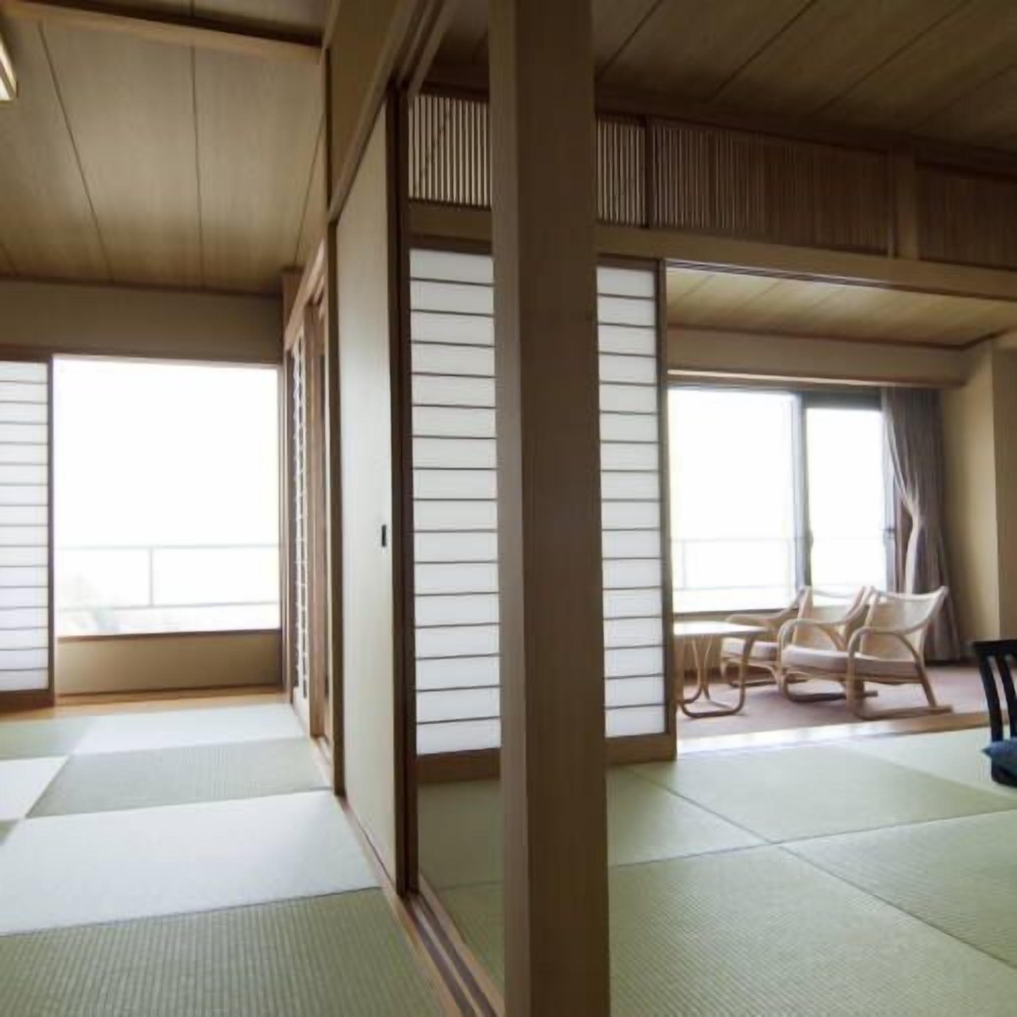 A traditional Japanese room with tatami flooring, sliding doors, and a seating area with chairs.