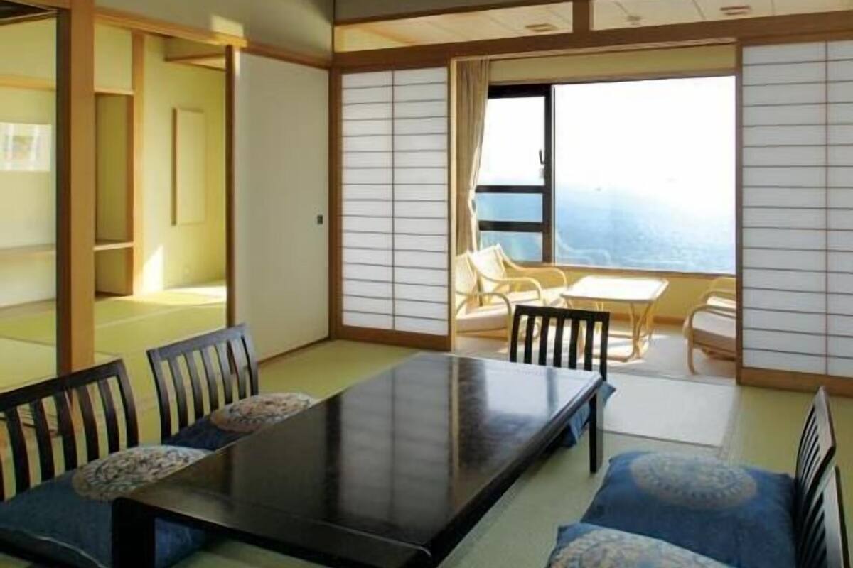 A traditional Japanese-style room with tatami flooring, a low table with chairs, and a sliding shoji screen door.