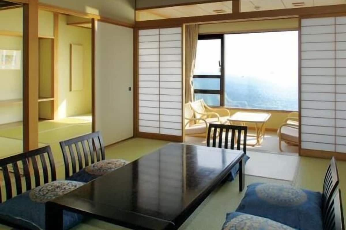 A traditional Japanese-style room with tatami flooring, a low table with chairs, and a sliding shoji screen door.