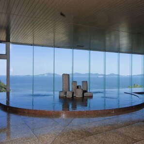 A modern interior with large windows offering a view of the sea and distant mountains. - Nishiura Onsen Hotel Tokaien (Gamagori)