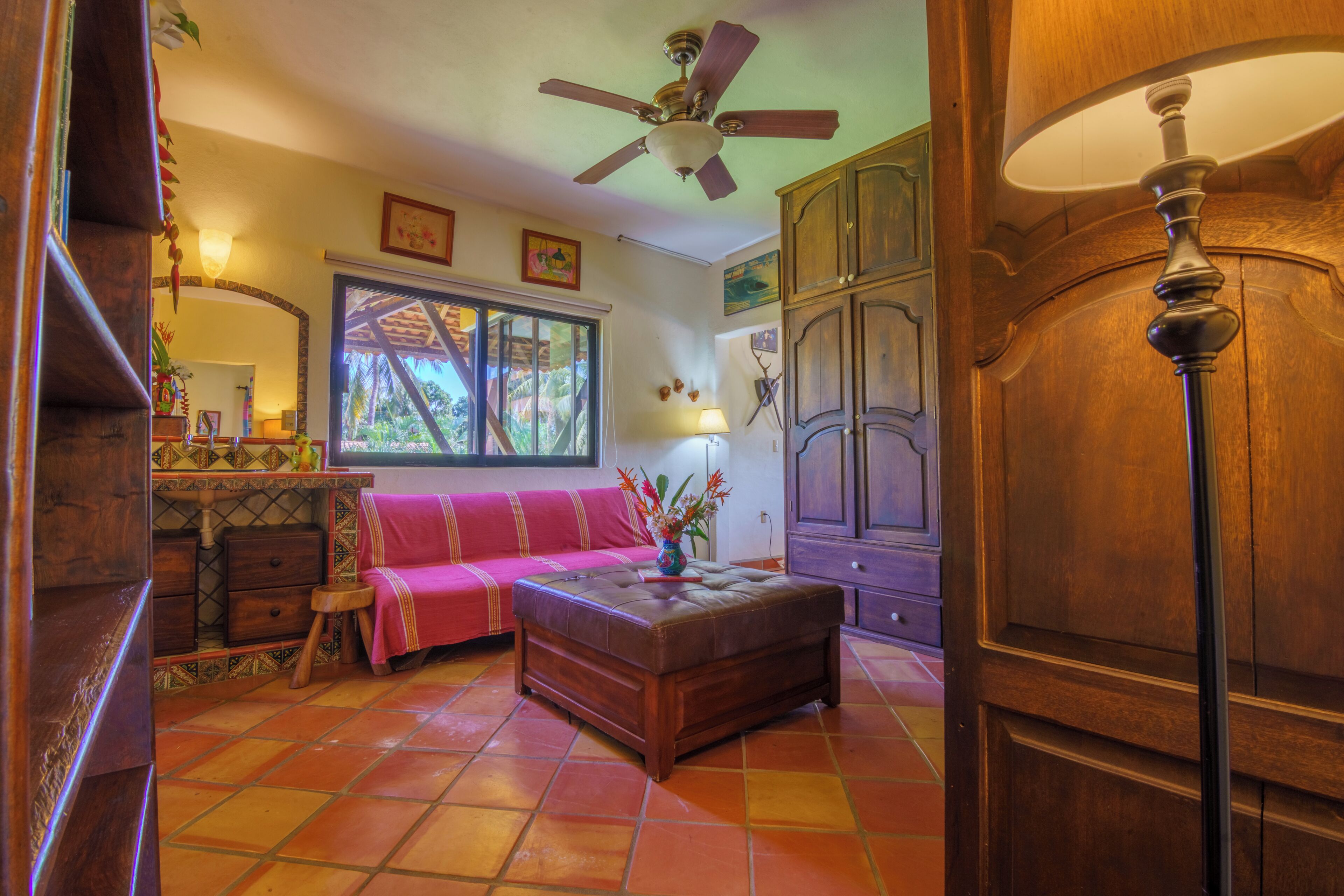 Ein Zimmer mit Deckenventilator, Fenster mit Blick, einer Couch, einem Schrank und einer Lampe.