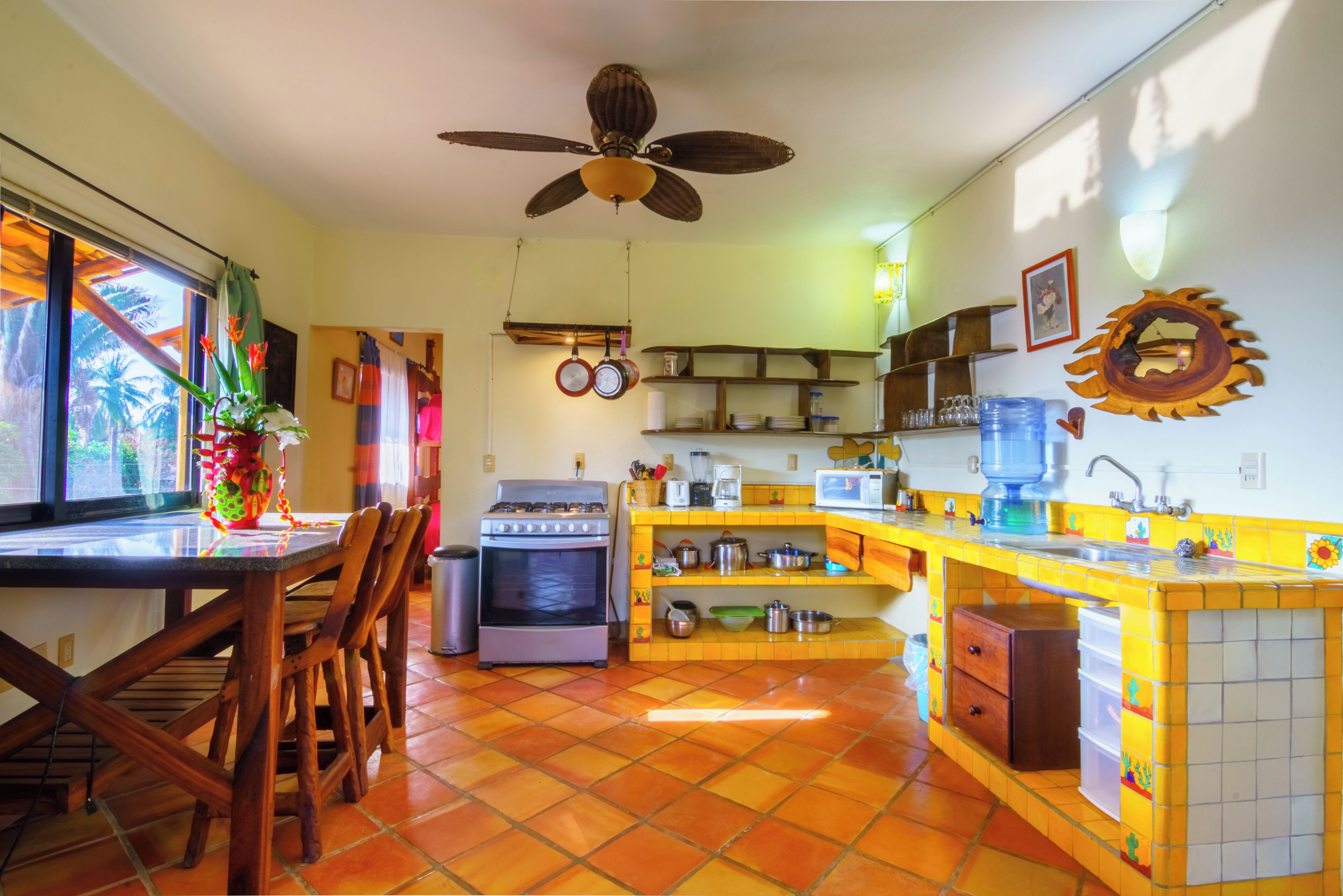 A kitchen with a stove, oven, and dining area with chairs.