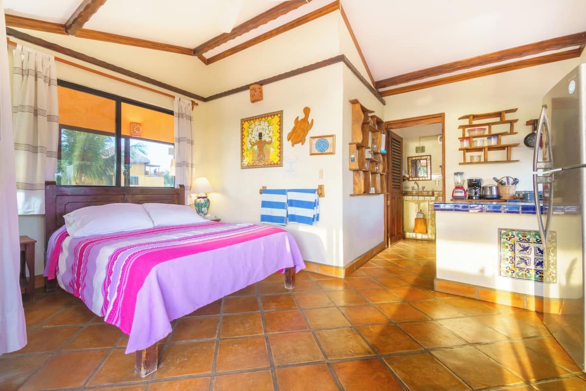 Una habitación con cama, zona de cocina y mesa de comedor.
