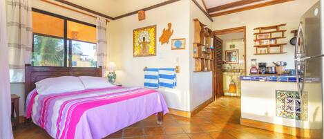 A room with a bed, a kitchen area, and a dining table.