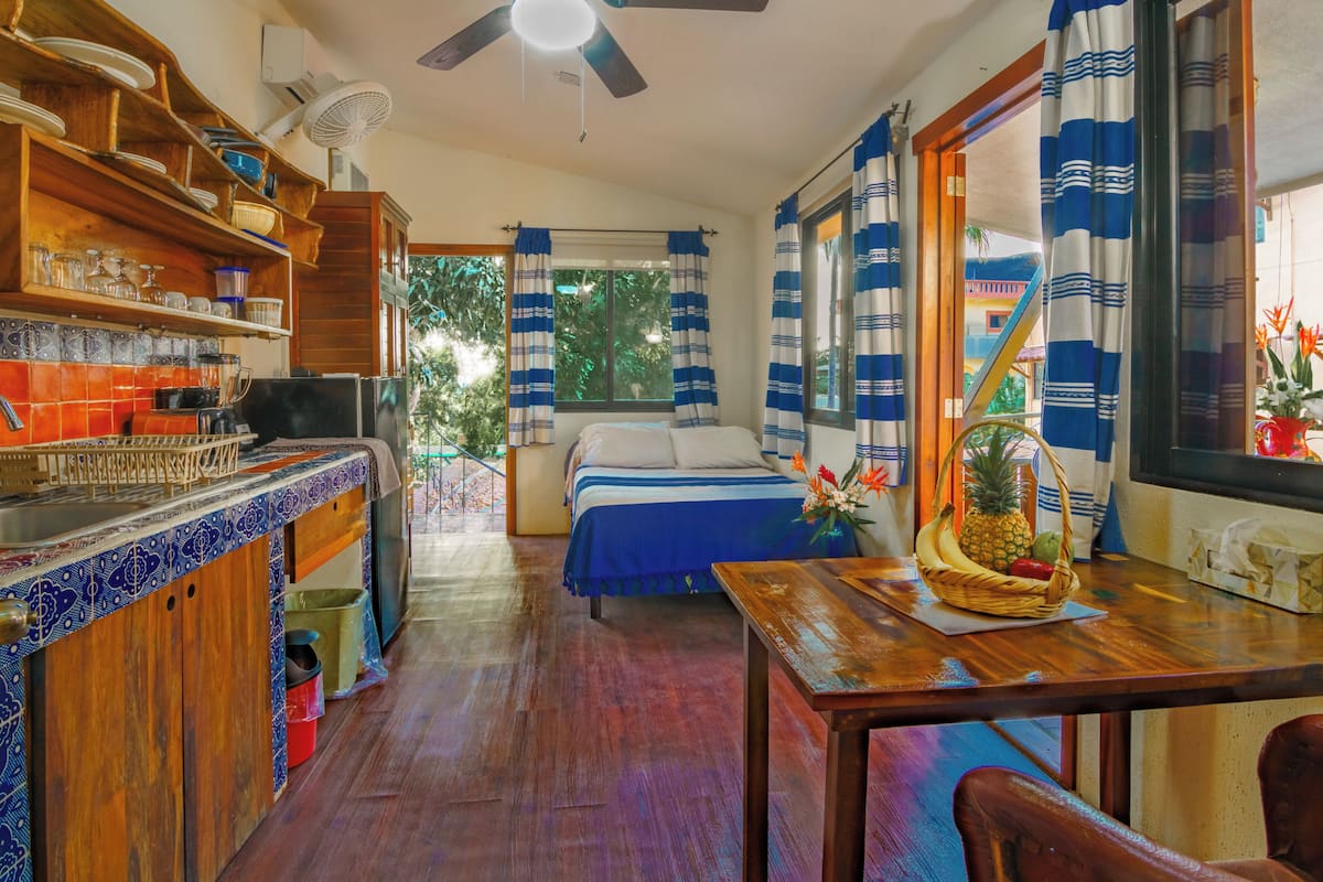 Una cocina compacta con zona de comedor, cama con vistas y ventilador de techo.