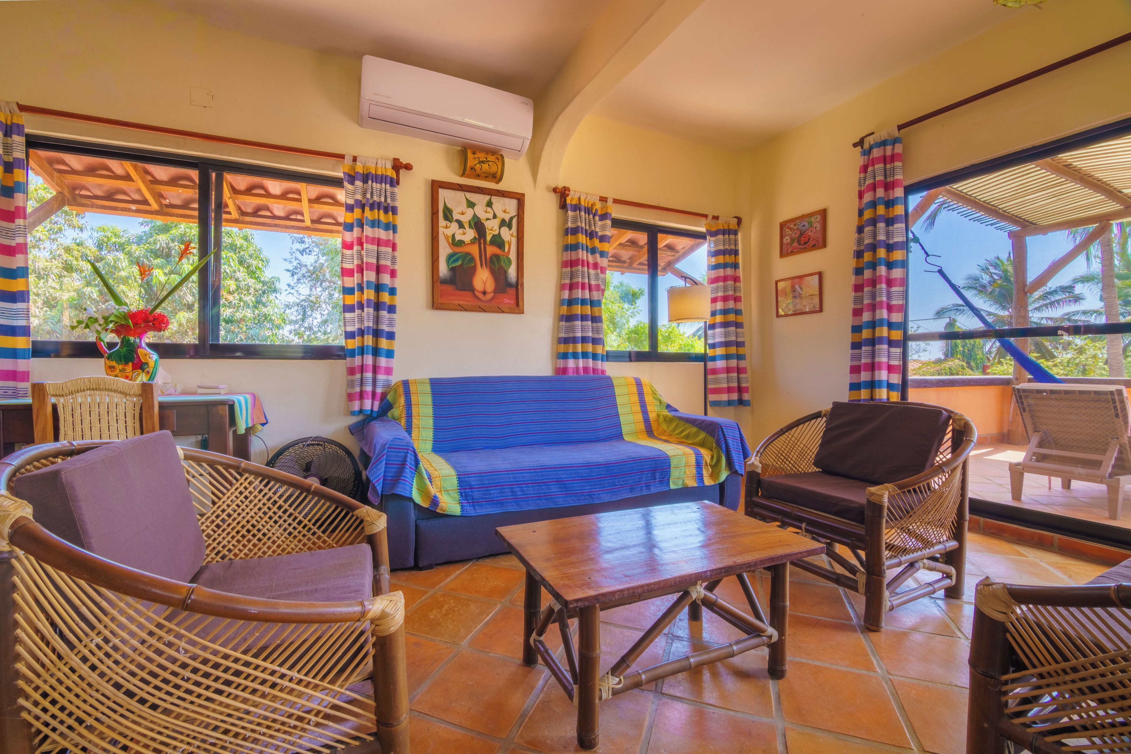 A room with a sofa, chairs, a table, and a window with curtains.