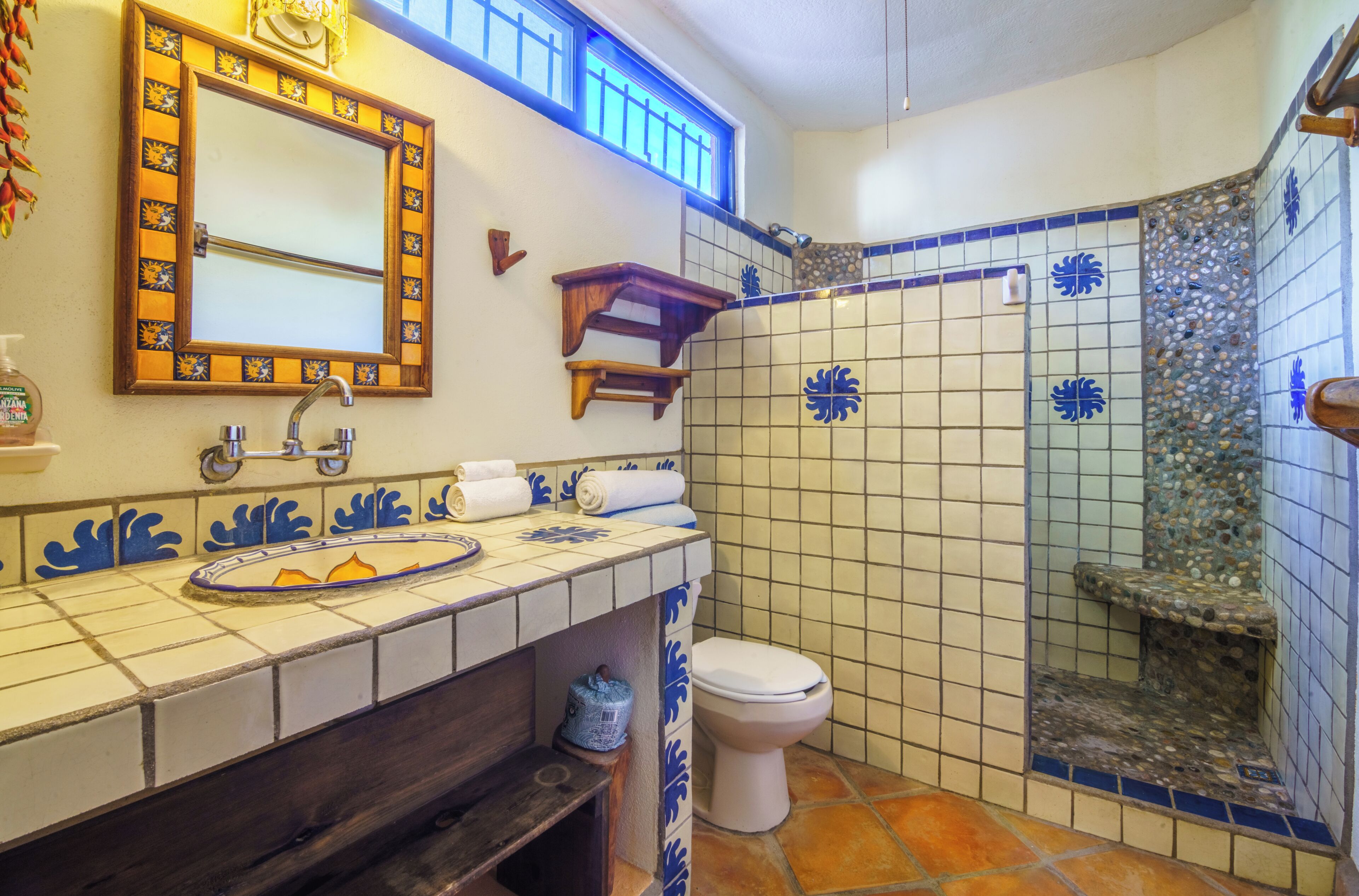 A bathroom with a sink, mirror, toilet, and shower area.
