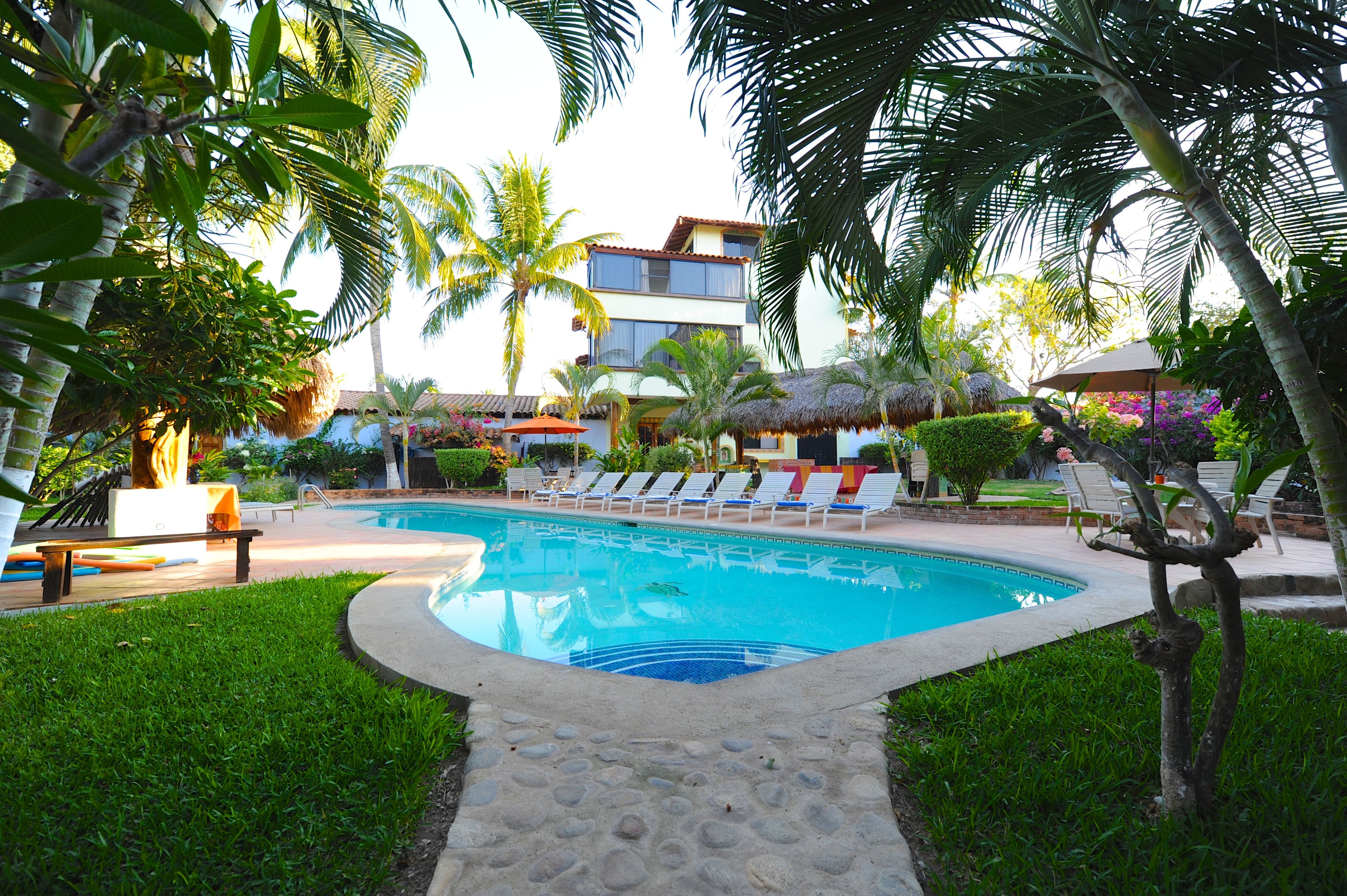 Una piscina al aire libre, sombrillas, tumbonas