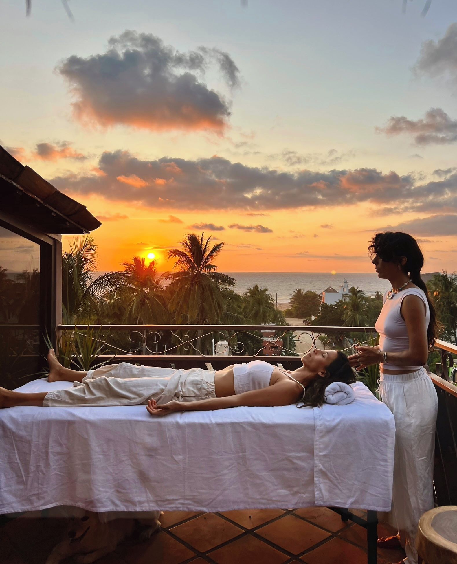 A massage therapy session on a balcony with a sunset view.