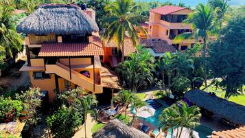 Un complejo turístico con varias edificaciones, piscina y palmeras.