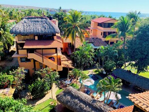 A resort with multiple buildings, a swimming pool, and palm trees. - Casamar Suites (Puerto Escondido)