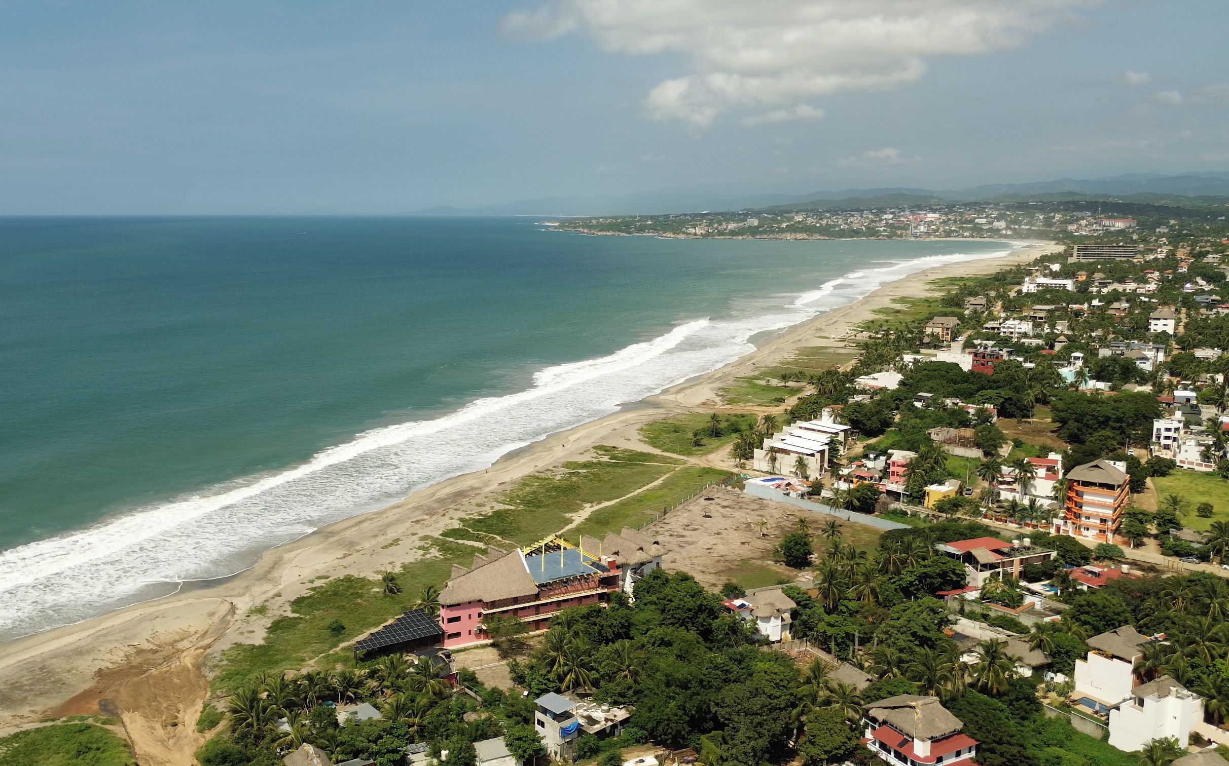 A coastal town with a beach, residential buildings, and a clear view of the ocean.