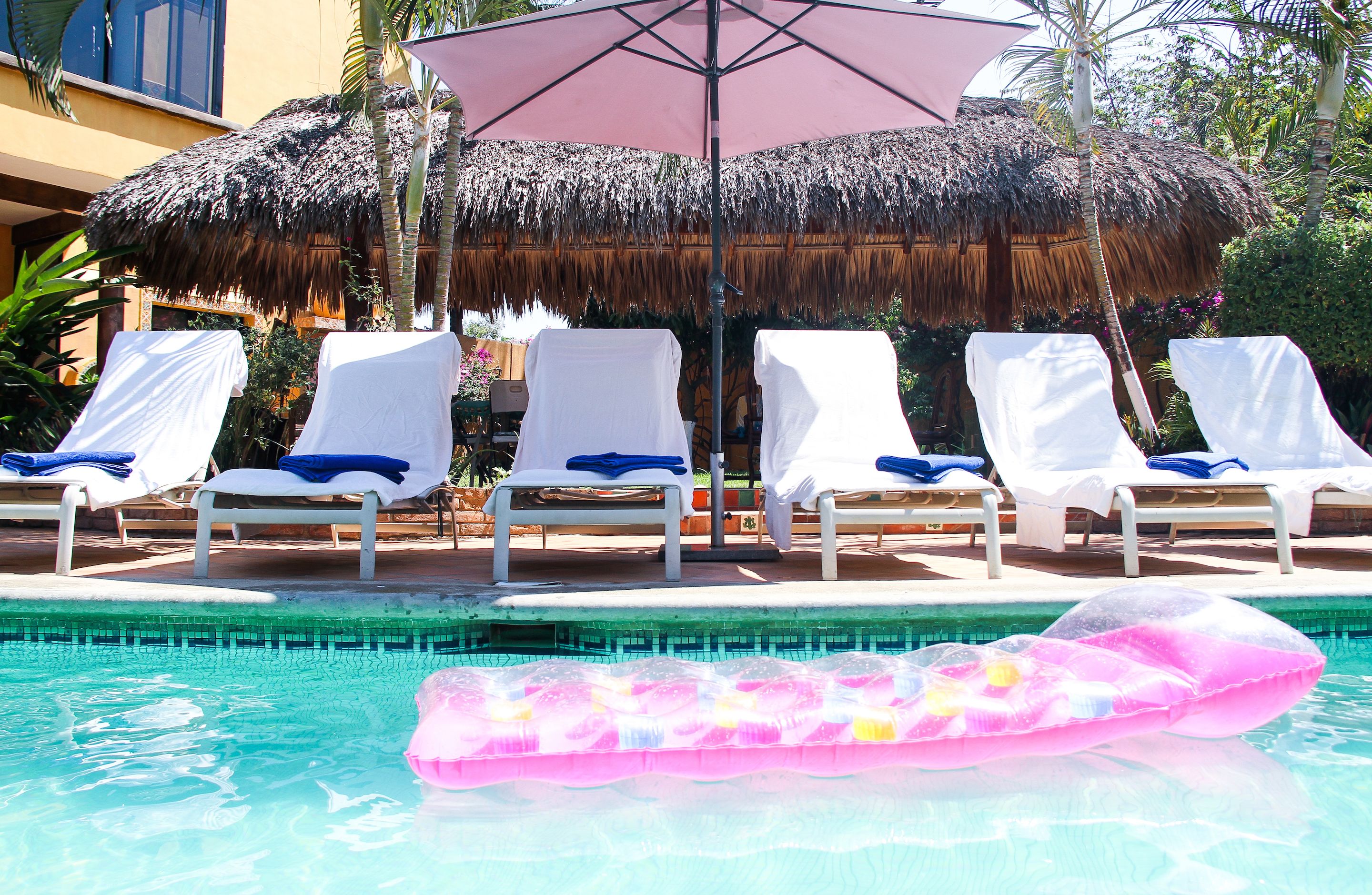 Una piscina al aire libre, sombrillas, sillones reclinables de piscina