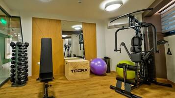 A gym with exercise equipment, a punching bag, and a mirrored wall.