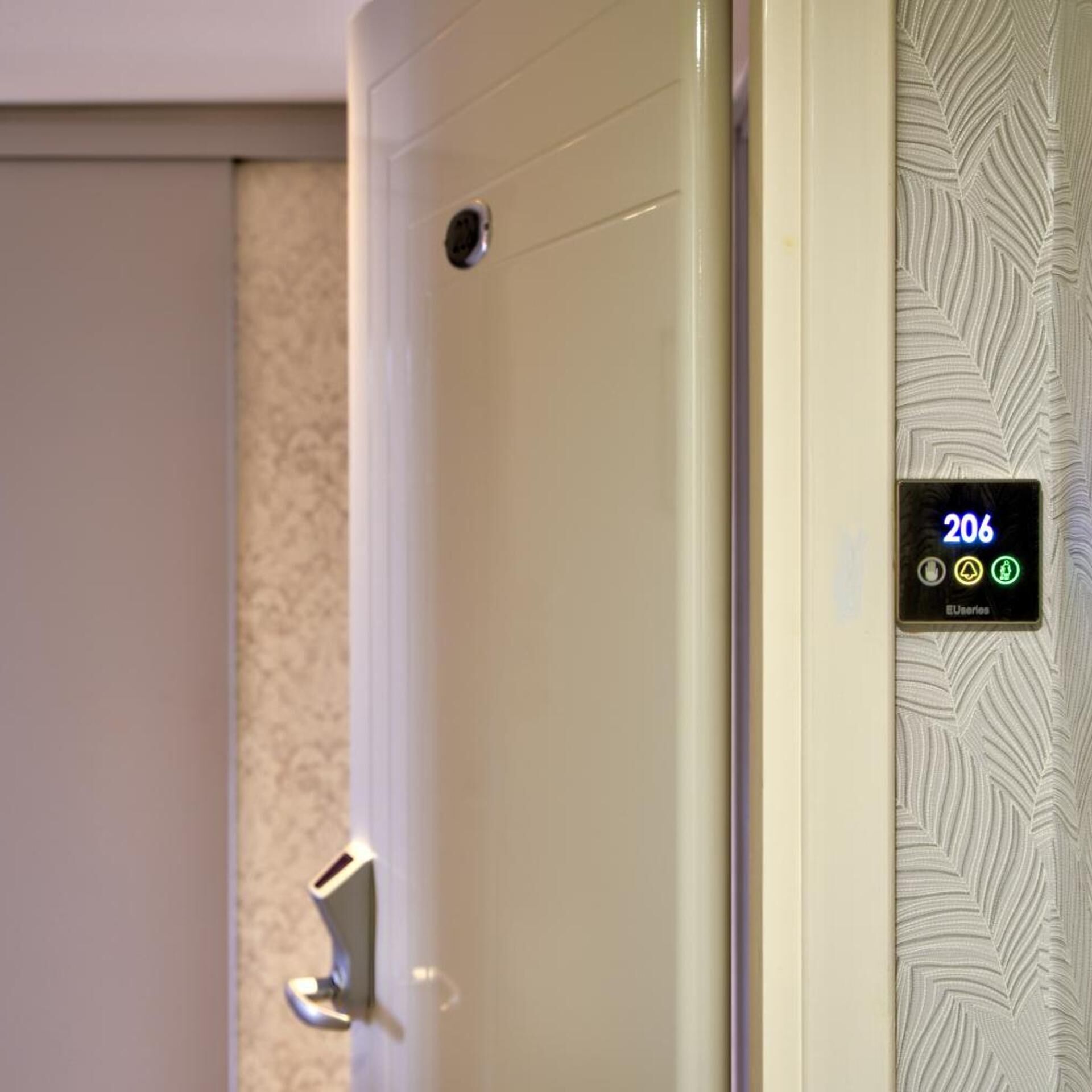 Une porte de chambre d’hôtel dotée d’une serrure électronique affichant le numéro 206 et d’un lecteur de carte magnétique.