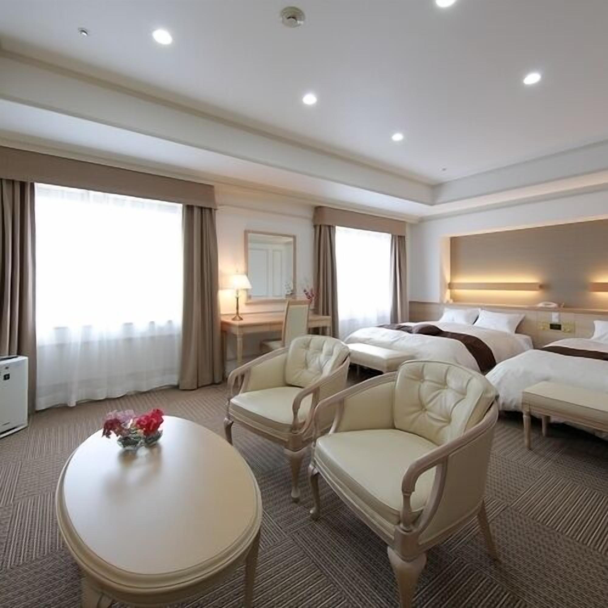 A hotel room with a bed, two chairs, a desk, and a table.