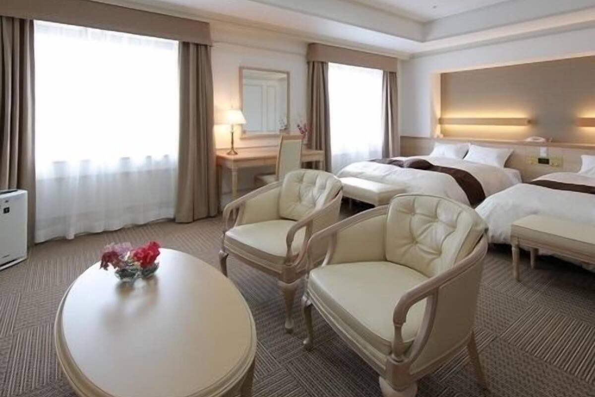 A hotel room with a bed, two chairs, a desk, and a table.