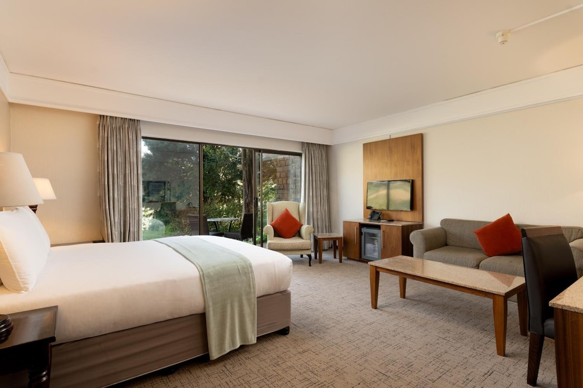 A hotel room with a bed, a sofa, a coffee table, and a television.