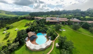 A large resort with a central swimming pool, multiple guest villas, and expansive green lawns. - Drakensberg Sun (Cathkin Park)