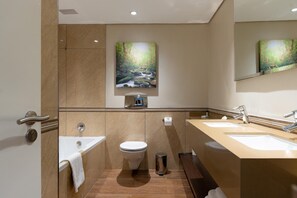 A modern bathroom with two sinks, a toilet, and a shower area. - Drakensberg Sun (Cathkin Park)