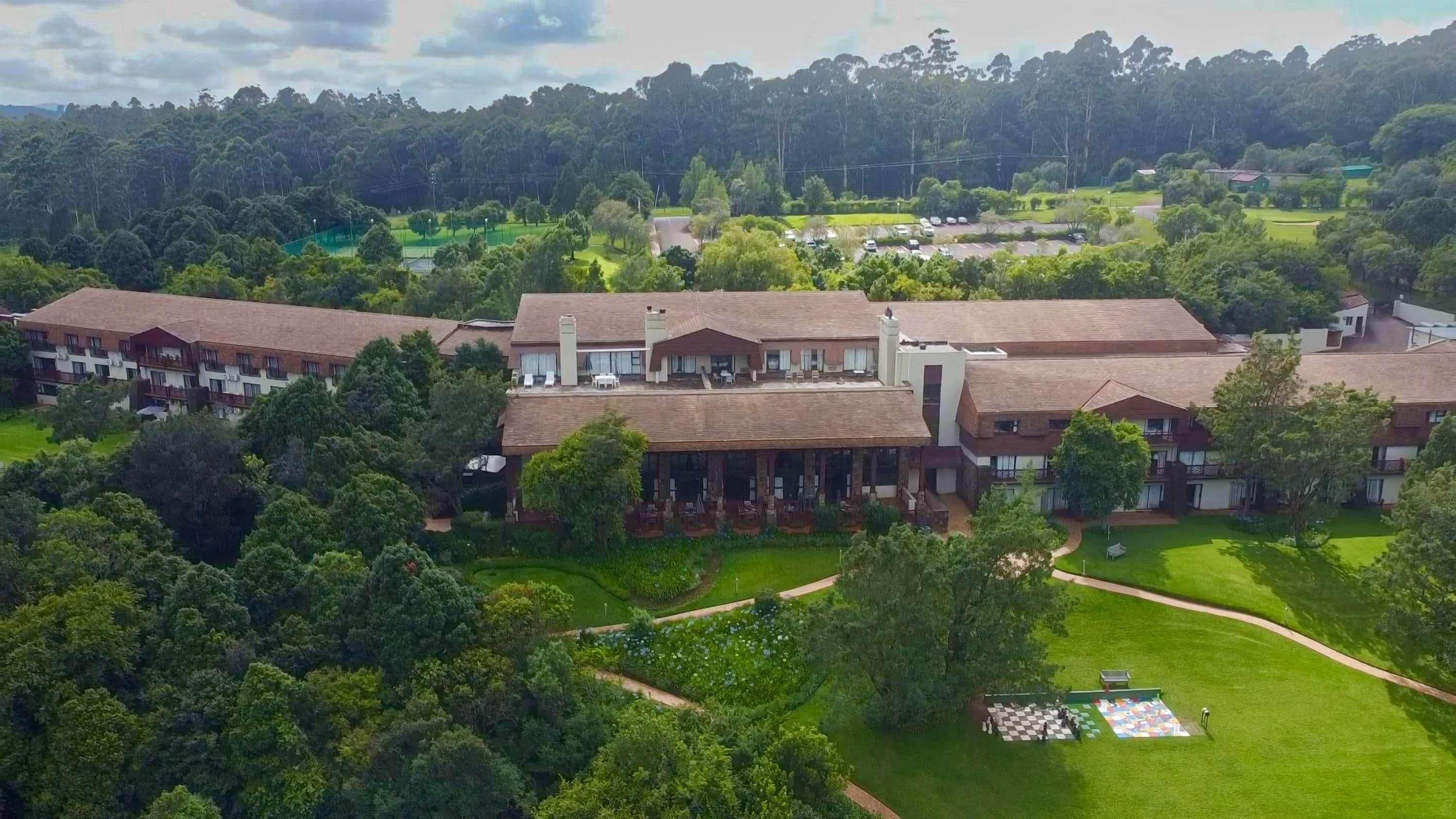 Een groot hotel met meerdere gebouwen, omringd door weelderige begroeiing en een golfbaan.