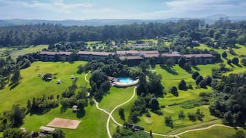 A golf course with a swimming pool, surrounded by lush greenery and a large building complex.