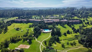 Un parcours de golf doté d’une piscine, entouré d’une végétation luxuriante et d’un vaste ensemble de bâtiments.