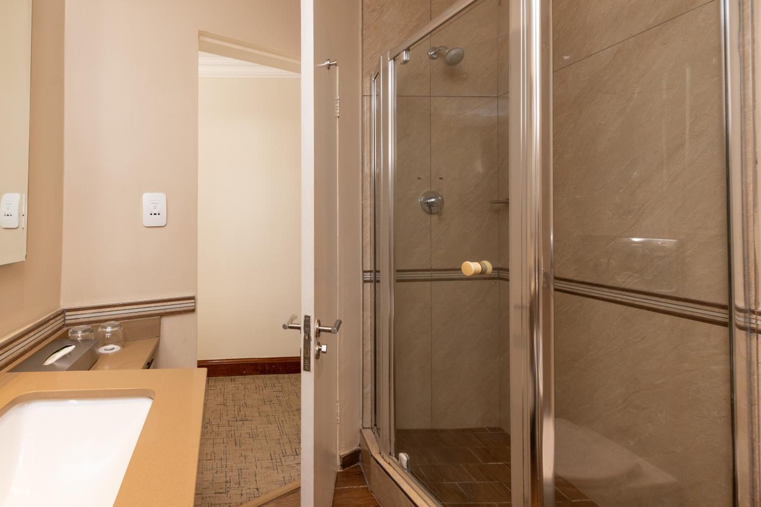 A bathroom with a glass-enclosed shower, a sink, and a mirror.