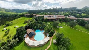 A large resort with a central swimming pool, multiple guest villas, and expansive green lawns. - Drakensberg Sun (Cathkin Park)