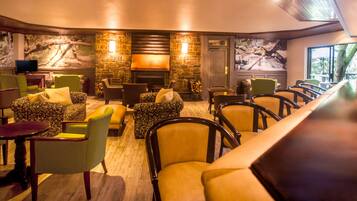 A cozy lounge area with comfortable seating, a fireplace, and a television.