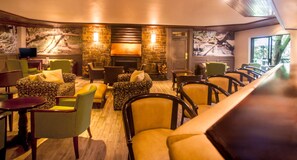 A cozy lounge area with comfortable seating, a fireplace, and a television. - Drakensberg Sun (Cathkin Park)