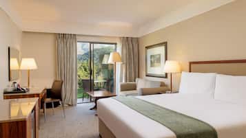 Une chambre d’hôtel avec un lit, deux chaises, un bureau et une vue sur l’extérieur.
