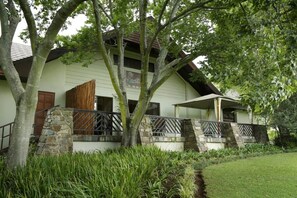 A two-story building with a stone staircase, a wooden door, and a balcony. - Drakensberg Sun (Cathkin Park)