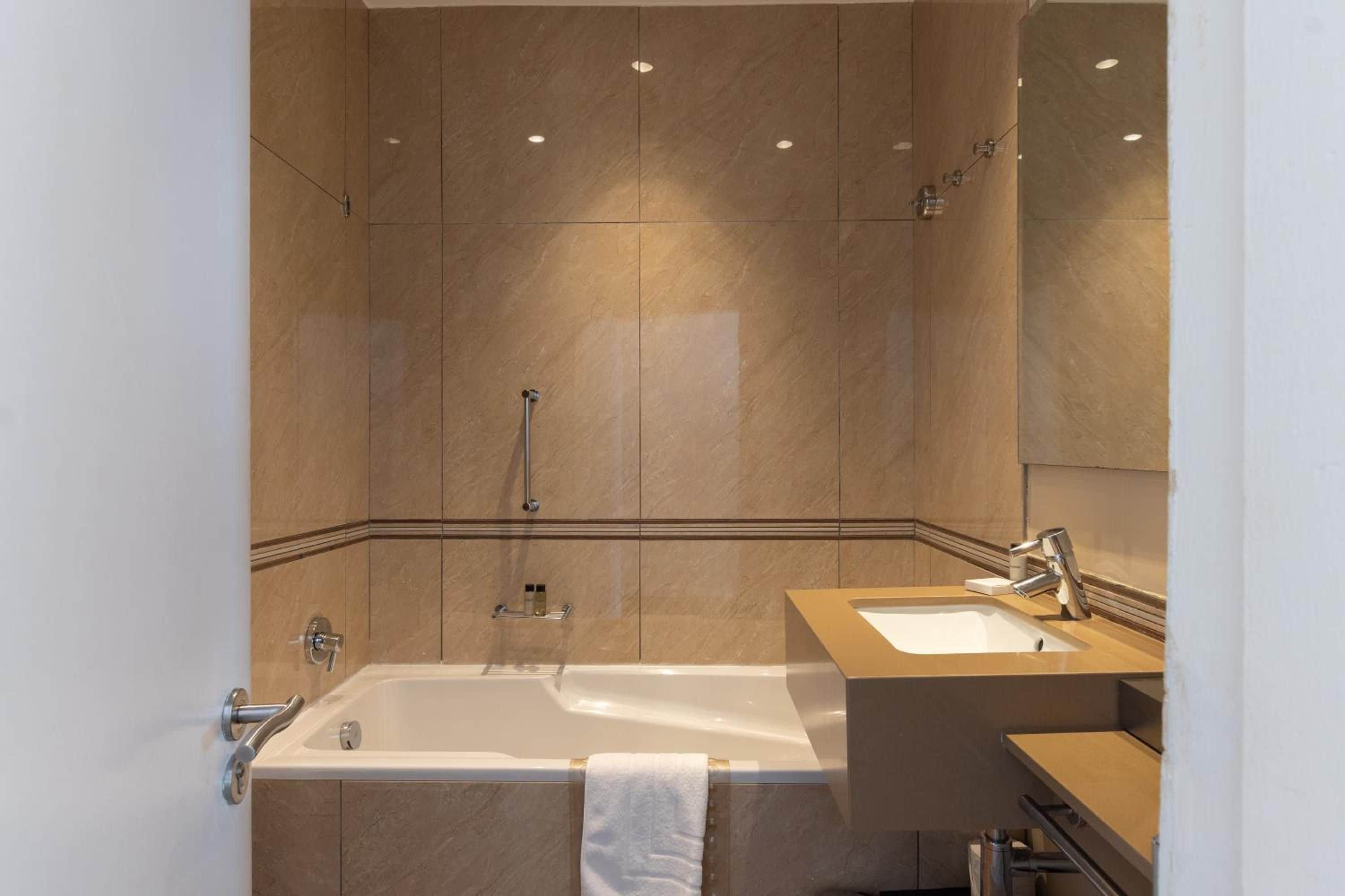 A modern bathroom with a bathtub, a sink, and a mirror.