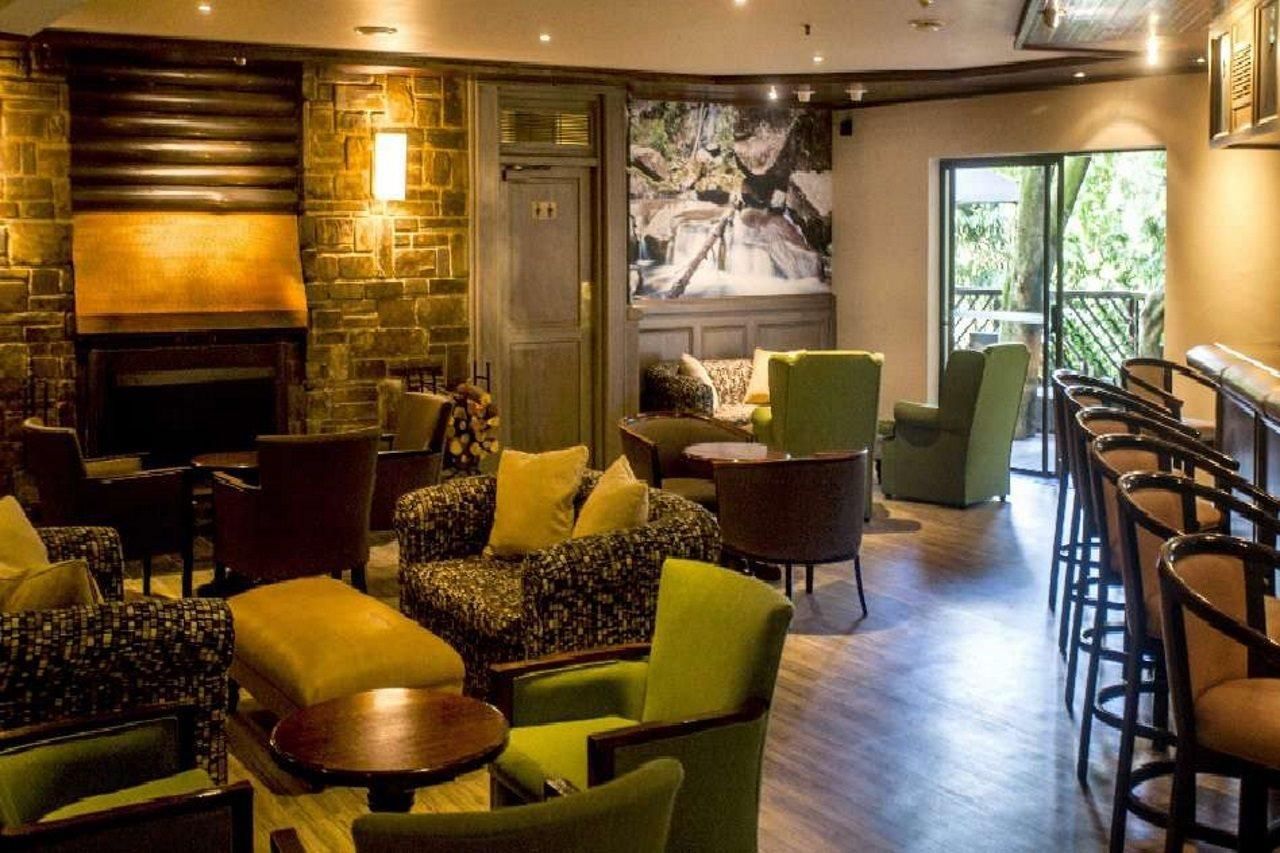 A cozy lounge area with a fireplace, comfortable seating, and a large window overlooking greenery.
