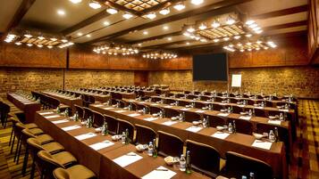 A conference room with multiple tables, chairs, and a large screen.