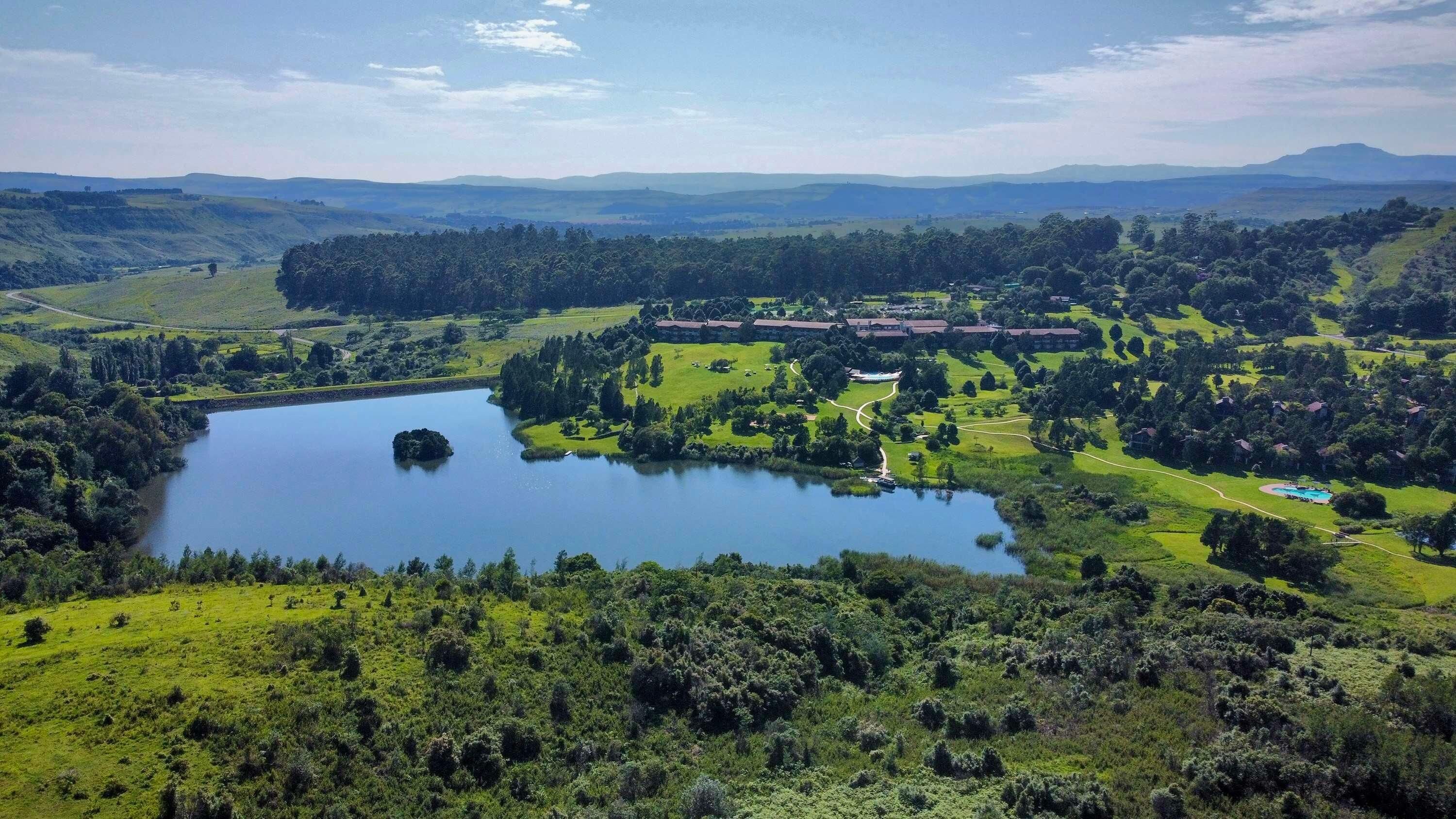 A large lake surrounded by lush greenery and a golf course. There are several buildings in the background, likely part of a resort or hotel.