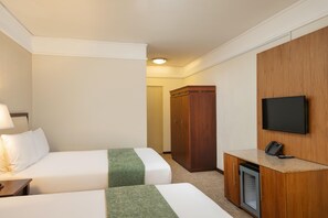A hotel room with two beds, a desk with a telephone, a television mounted on the wall, and a wardrobe. - Drakensberg Sun (Cathkin Park)