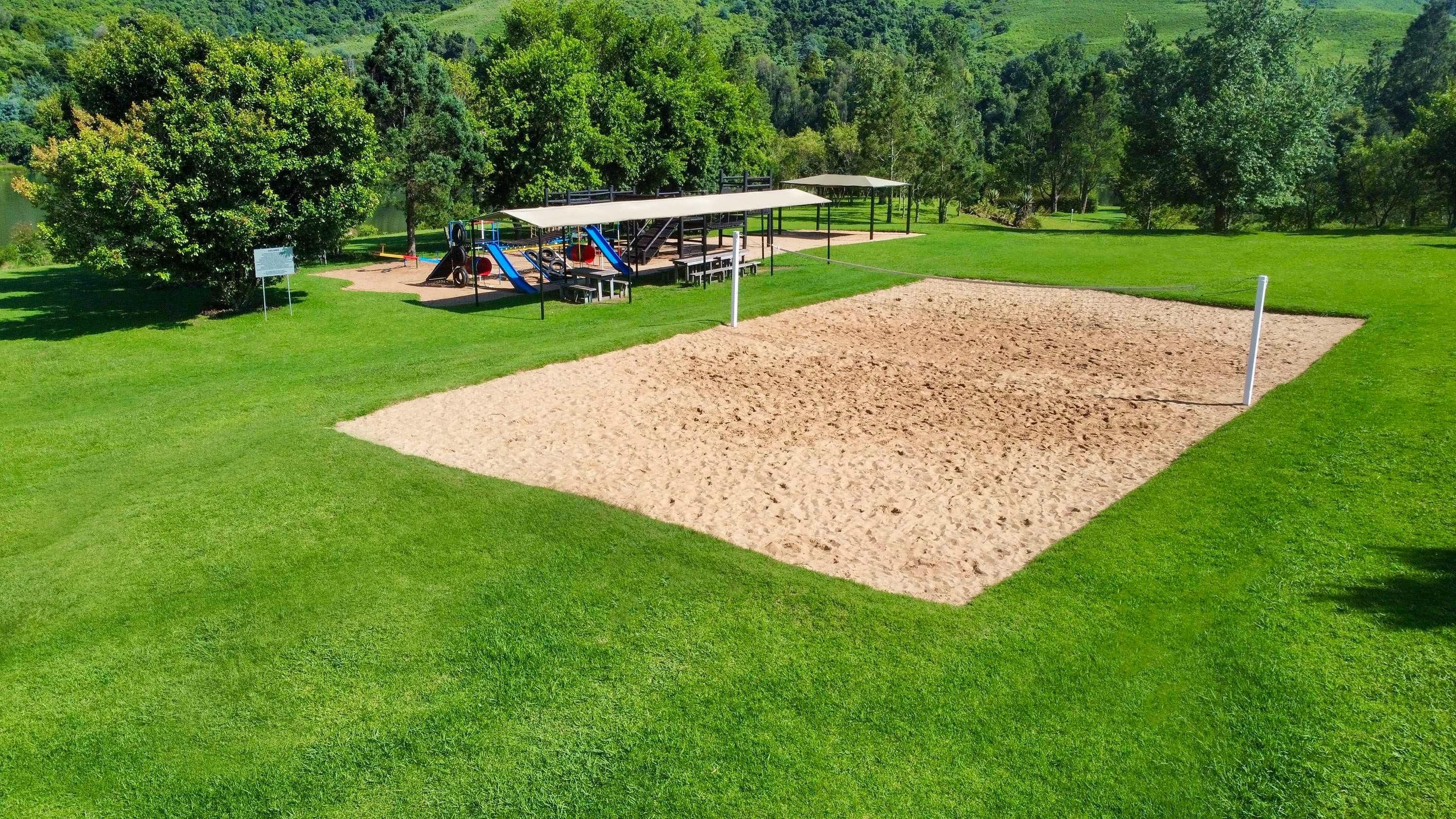 A park with a sandbox, playground equipment, and picnic tables.