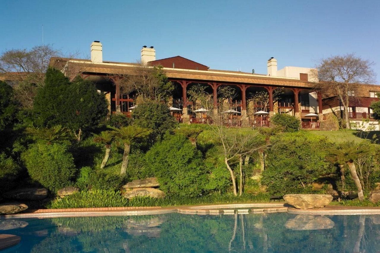 A hotel with a pool, outdoor seating, and a landscaped garden.