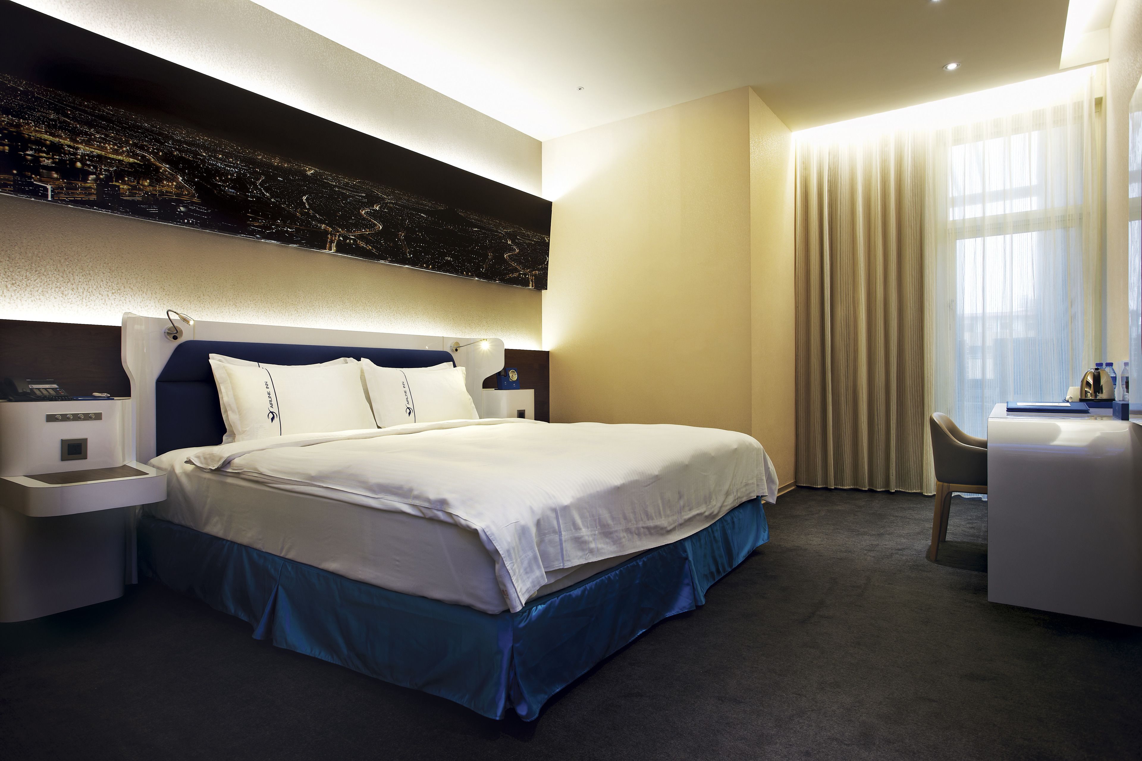 Una habitación de hotel moderna con una cama grande, un escritorio y vistas de la ciudad de noche.