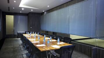 A conference room with a long table, chairs, water bottles, and a large window with blinds.