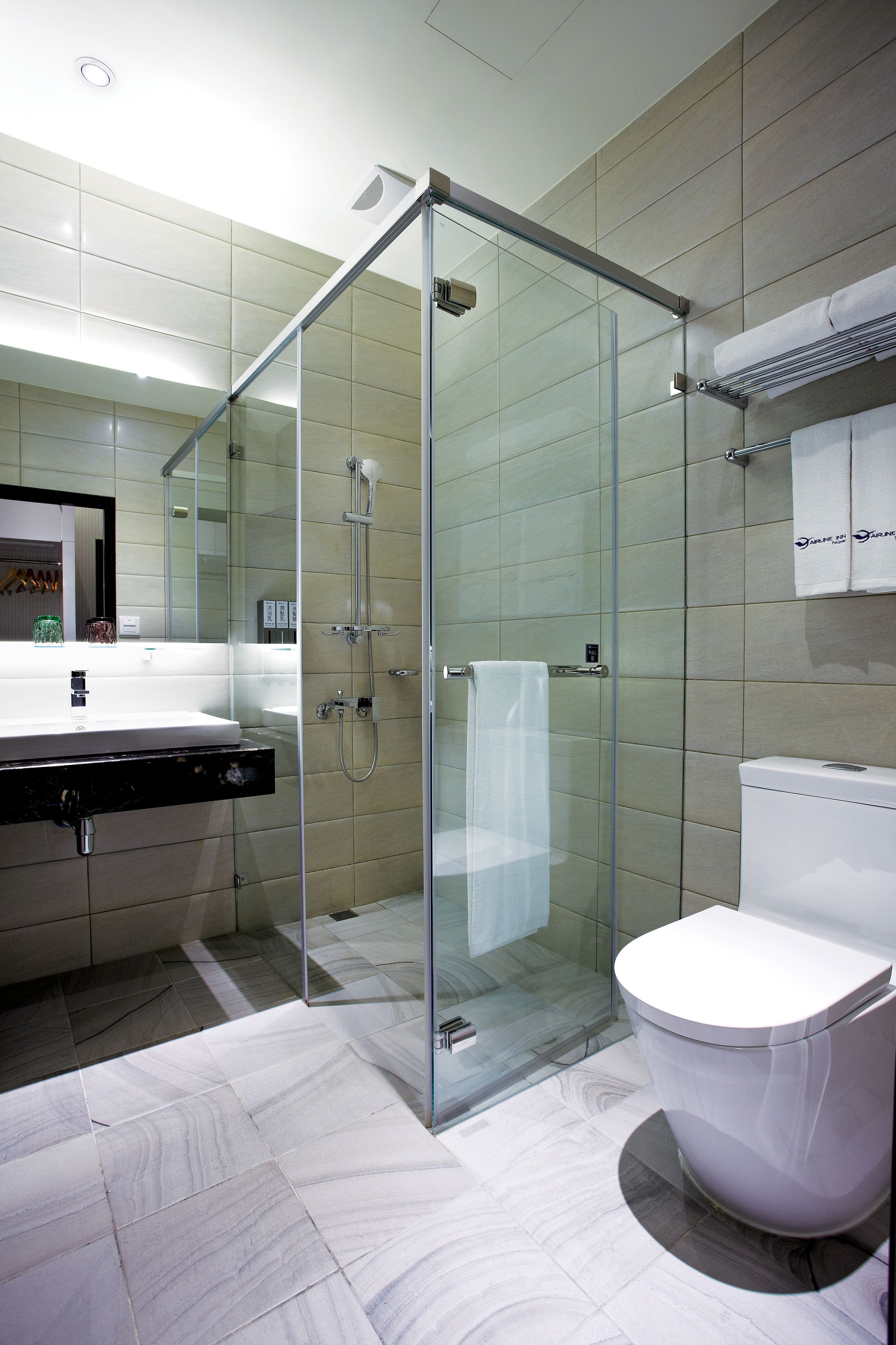 A modern bathroom with a glass-enclosed shower, a white sink, and a toilet.