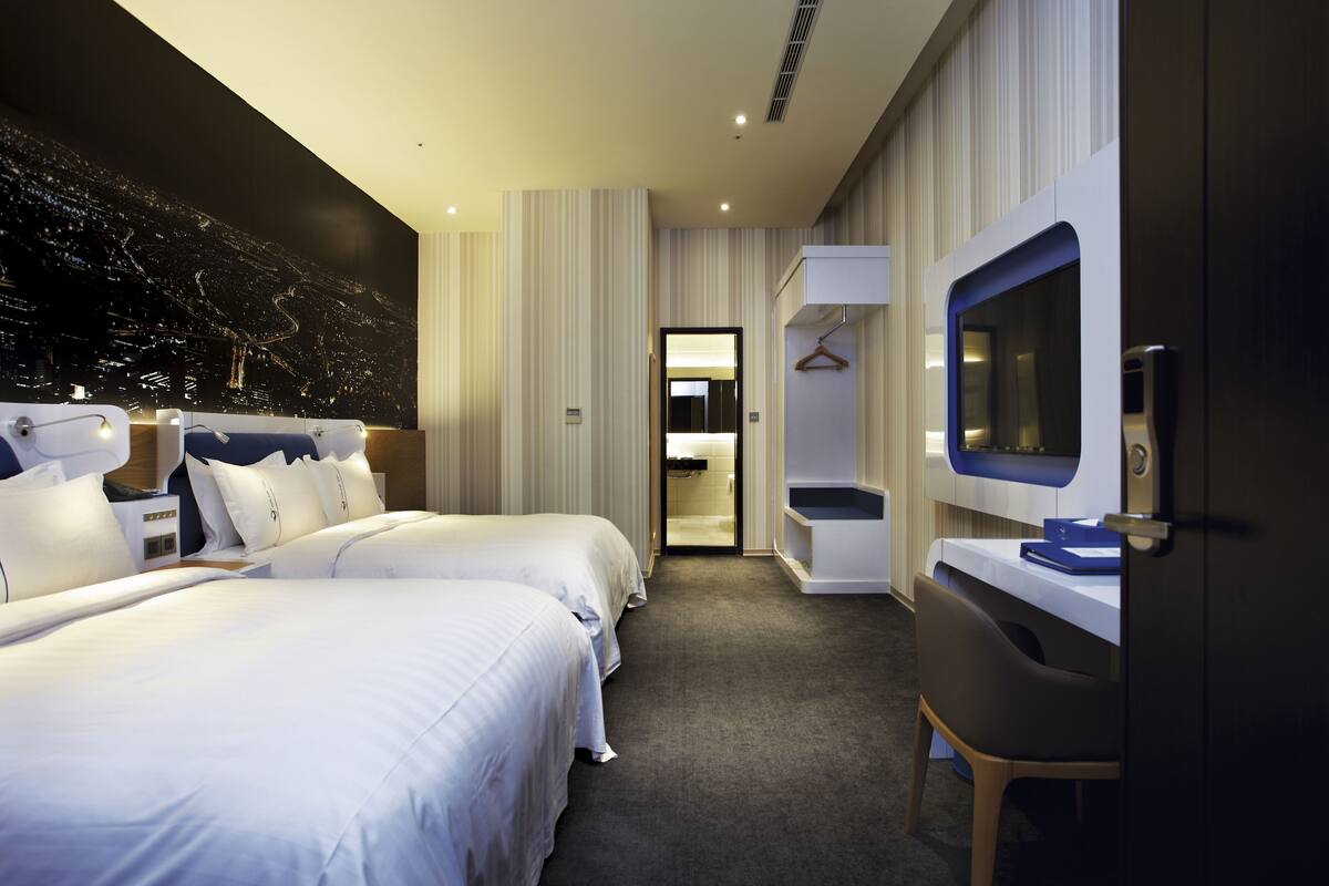 Une chambre d’hôtel avec deux lits, une télévision, un bureau et un coin salon.