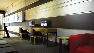 Un espace de bureau moderne comprenant un bureau, deux chaises, un canapé rouge et un écran fixé au mur.