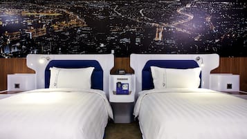 A hotel room with two beds, a nightstand with a clock, and a cityscape view.